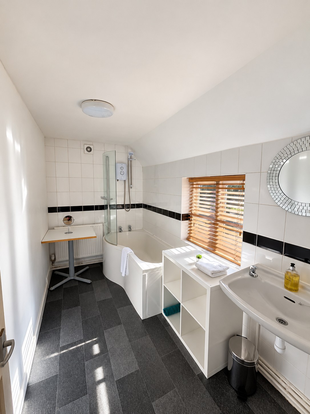 The apartment bathroom with a bath, overhead shower, basin and tiled walls