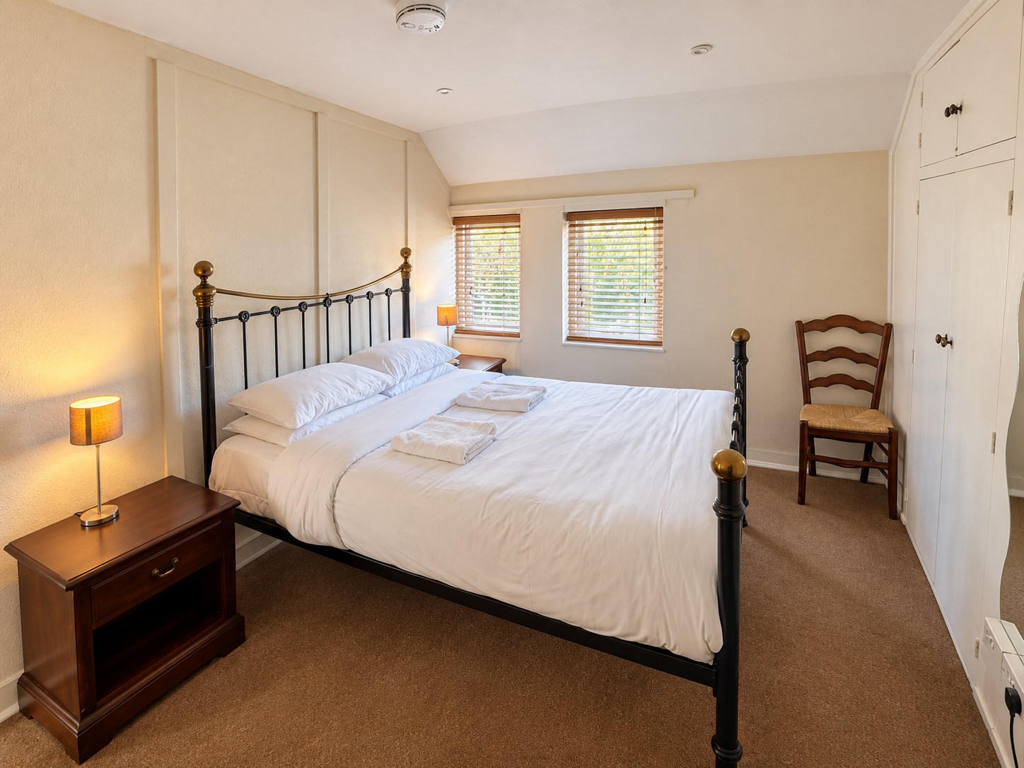 Bedroom One at The Fox Inn, with an iron bed, white bedding and warm bedside lamps