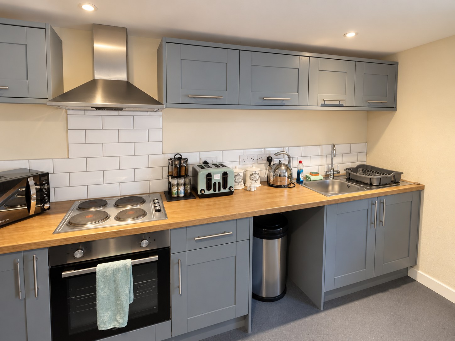 The apartment kitchen with grey cabinets, wooden worktops, oven, hob and sink