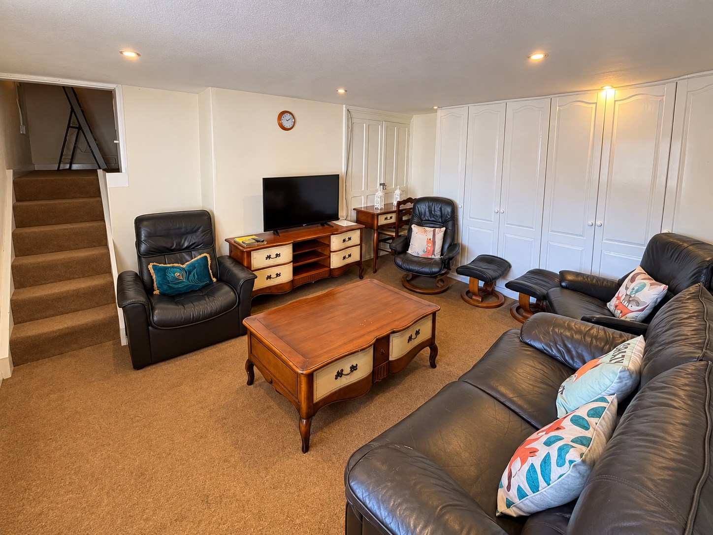 The apartment lounge with leather seating, a wooden coffee table and television